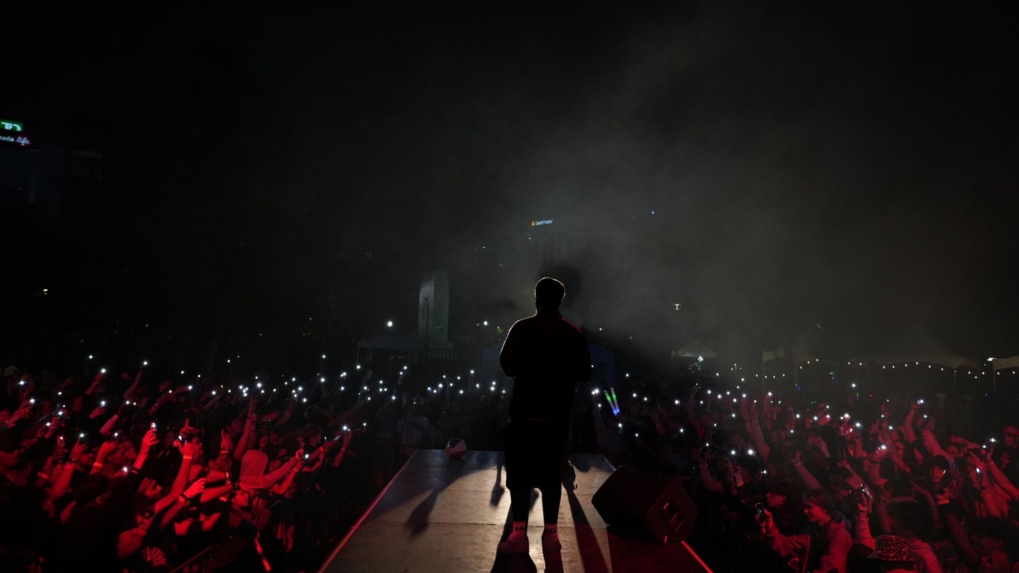 Harman 2x on stage facing a crowd holding up phone lights